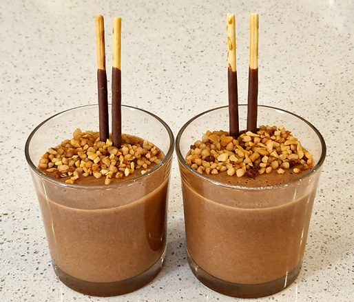 Chocolademousse praliné in een glas met twee mikado stokjes en nougatine