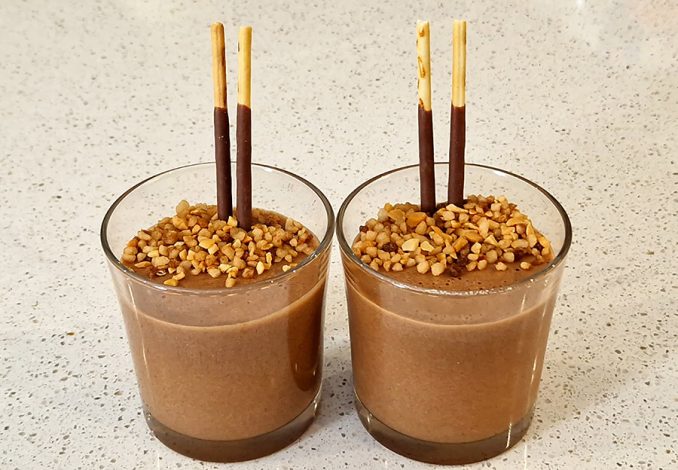 Chocolademousse praliné in een glas met twee mikado stokjes en nougatine