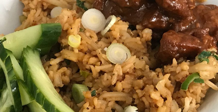 Nasi goreng op bord met komkommer en sate