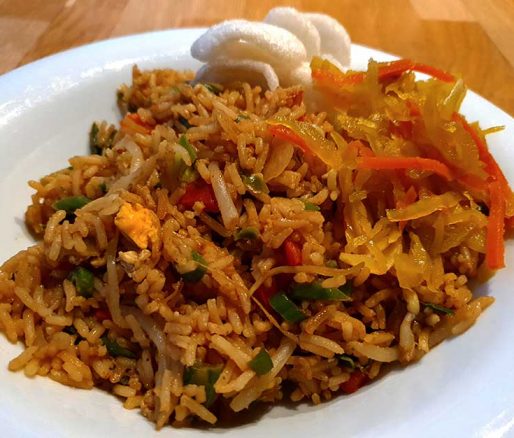 Nasi goreng gepresenteerd op bord met kroepoek en atjar