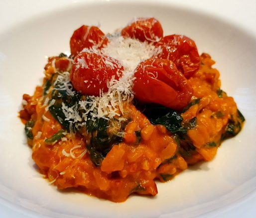Risotto met tomaat en spinazie op een bord