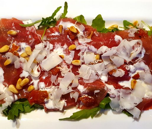 Carpaccio op een bedje van rucola en schapenkaas en gebrande pijnboompitten