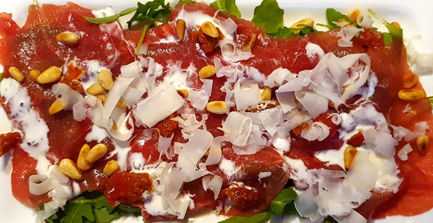 Carpaccio op een bedje van rucola en schapenkaas en gebrande pijnboompitten