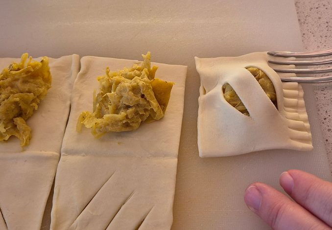 Bladerdeeg vullen met pulled chicken voor zelfgemaakte kip-kerriehapjes.
